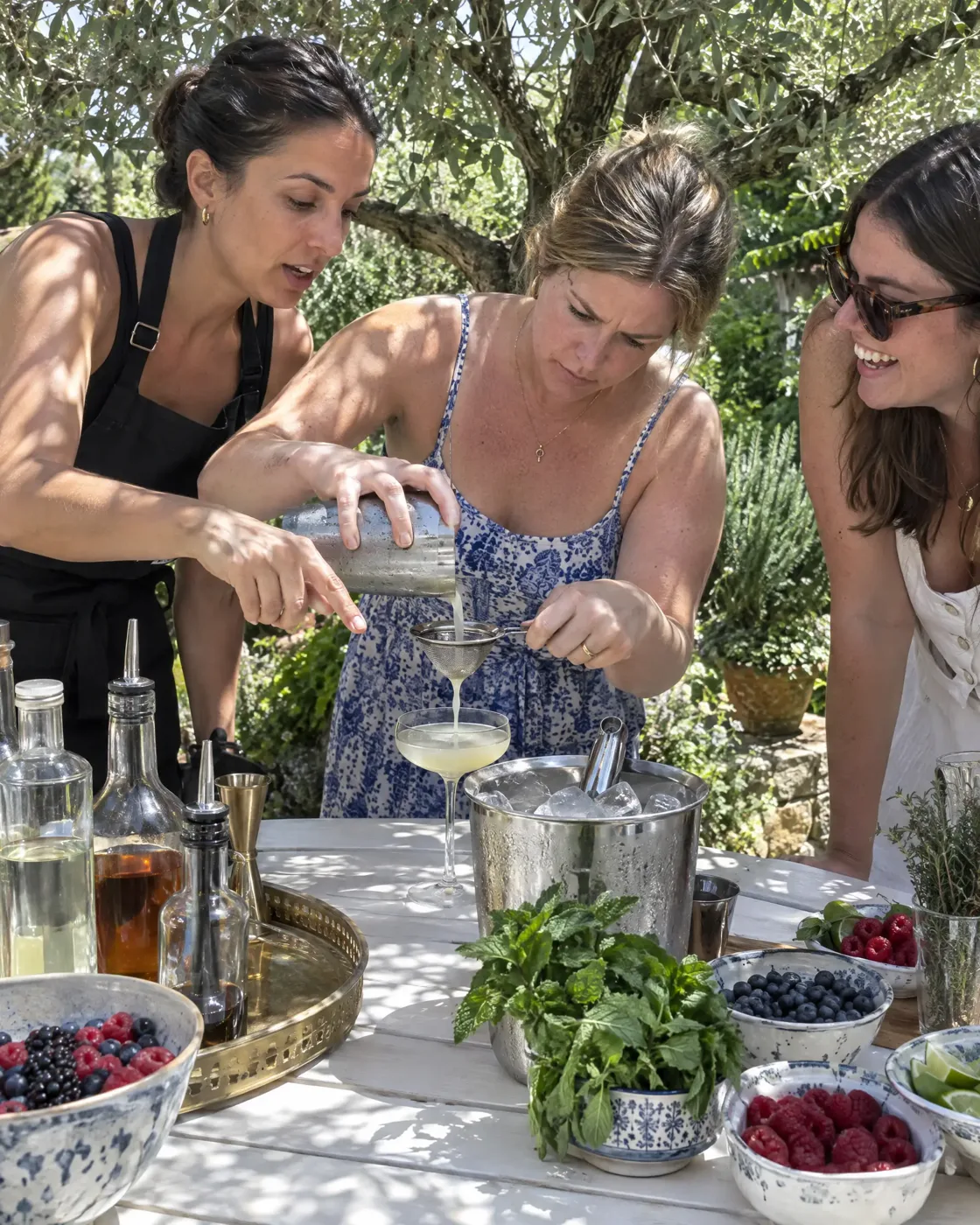 ברמנית מלמדת משתתפת לסנן קוקטייל בסדנת קוקטיילים בגינה